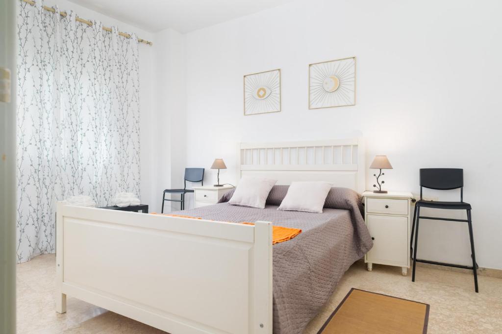 a white bedroom with a bed and two chairs at LuxSevilla Apartment Piscina in Bormujos