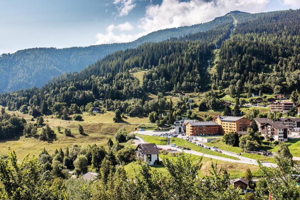 a town in the mountains with trees and buildings at SWISSPEAK Resorts by Pierre & Vacances Premium Vercorin in Vercorin