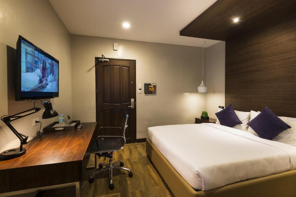 a bedroom with a bed and a desk and a television at Kklc Test in Phumĭ Chăm Yéam