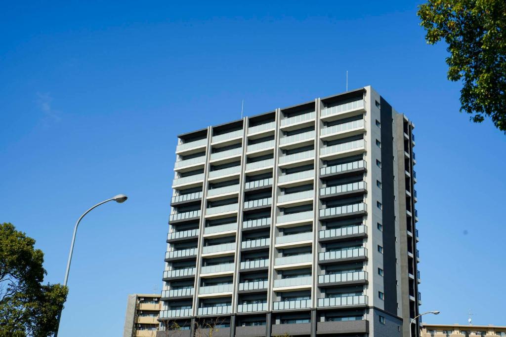 a tall white building with a blue sky in the background at Formosa Hills in Kumamoto
