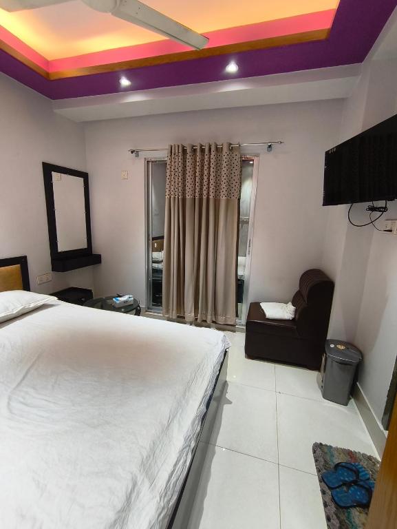 a bedroom with a white bed and a couch at Hotel Pink Orchid in Chittagong