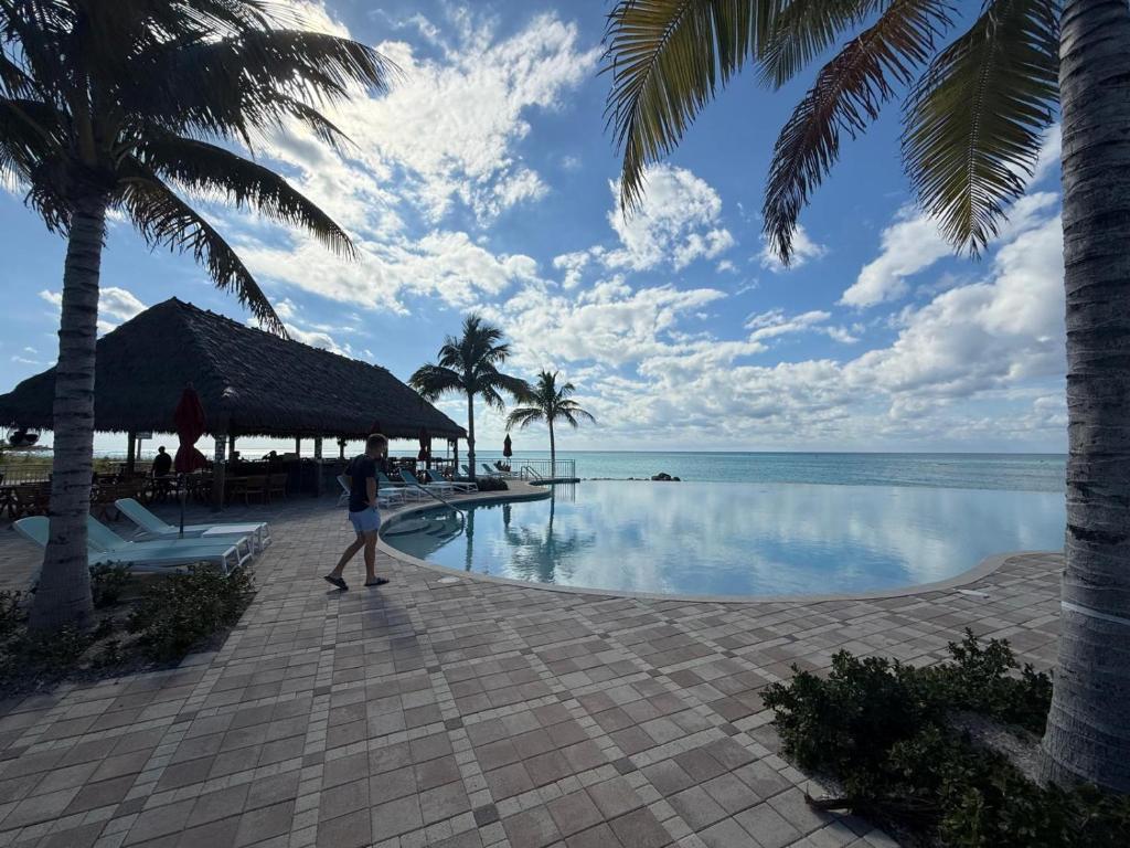 a woman walking by a swimming pool next to the ocean at Bimini Paradies South Bimini North Bimini Bahamas Bimini 10B Alice Town in South Bimini