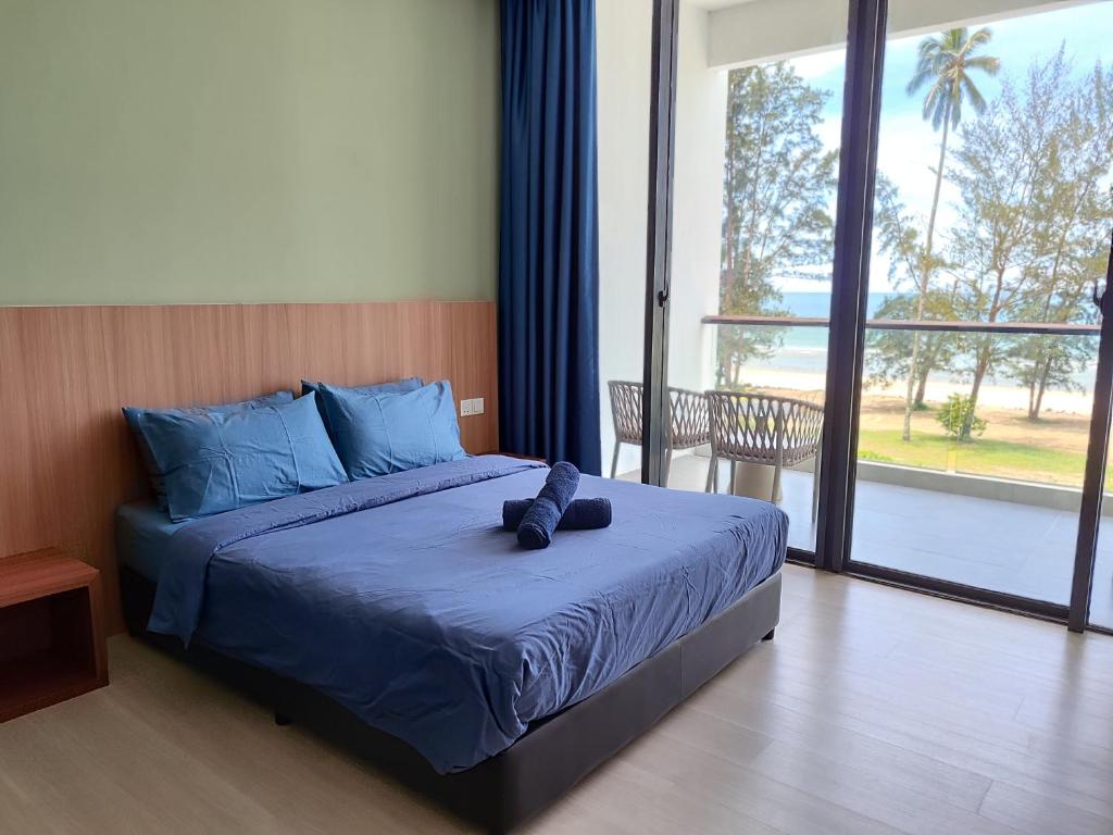 a bedroom with a bed with blue sheets and a large window at Sematan Roxy Beach Apartment in Sematan