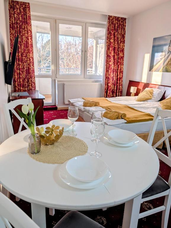 a white table and chairs in a room with two beds at M-Apartamenty in Kołobrzeg
