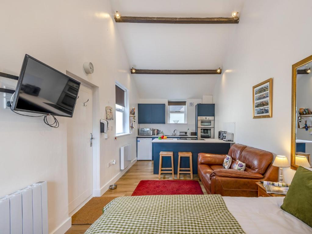 a living room with a couch and a tv and a kitchen at The Gables Studio in Keswick
