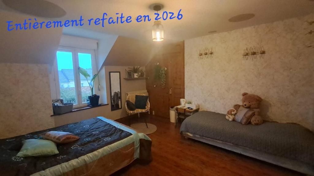 a bedroom with two beds and a teddy bear sitting on the bed at Au Moulin de la Tour in La Malmaison