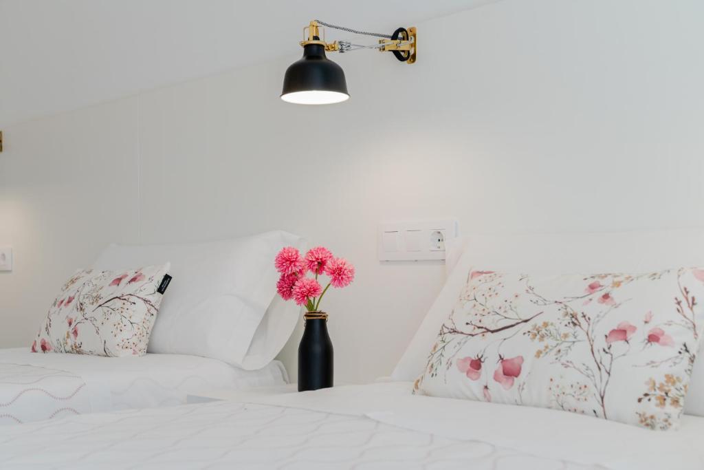 a bedroom with a bed with pink flowers in a vase at Hostal La Isla in Carboneras