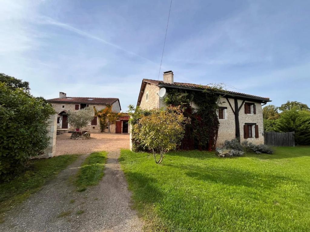 an old stone house with a grassy yard at Fontaine de Champagne in Champagne-et-Fontaine