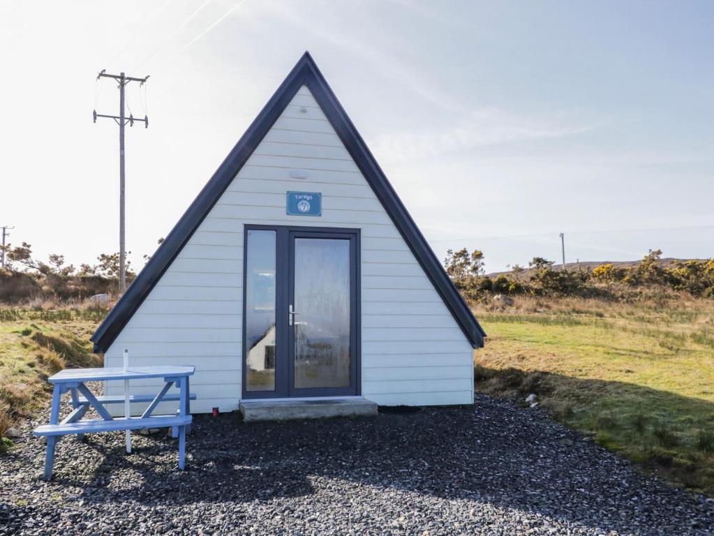 a small house with a blue bench in front of it at Cabin 7 Toraigh in Gortahork