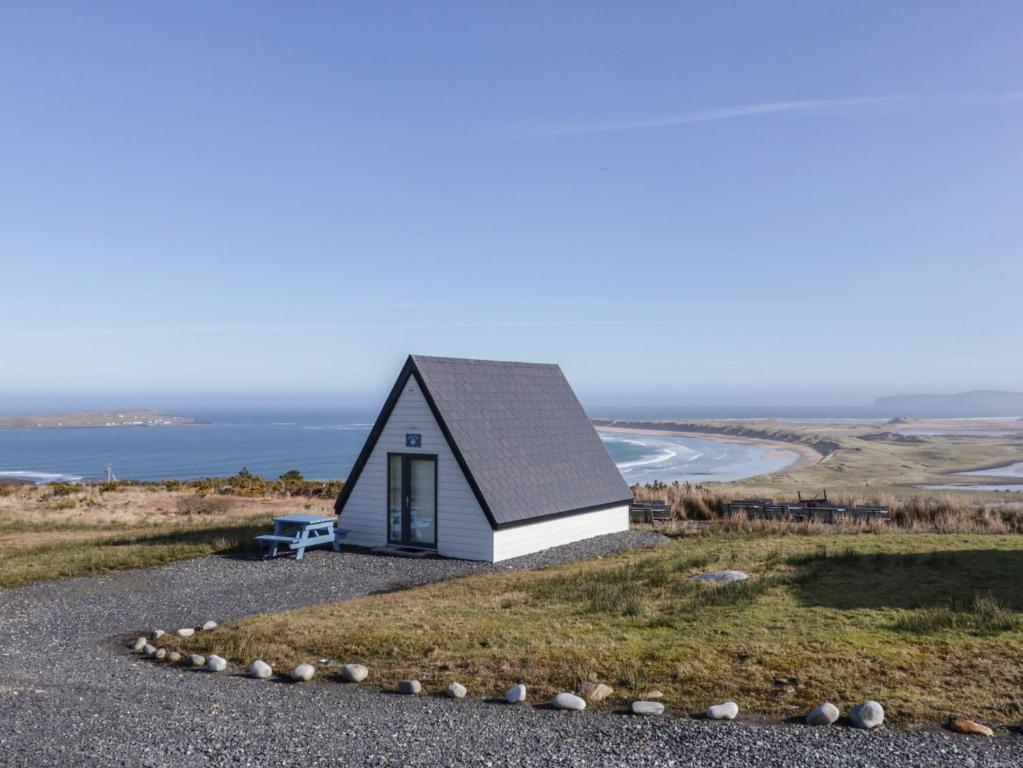 a small house on a hill near the ocean at Cabin 6 An Mhucais in Gortahork