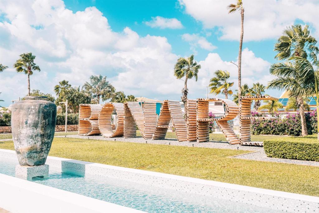 a sign in a park with palm trees at Van der Valk Plaza Resort Bonaire - All Inclusive in Kralendijk