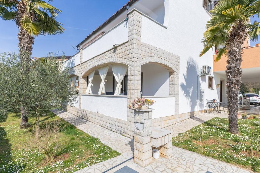 a white house with palm trees in front of it at Apartments Koraca in Poreč