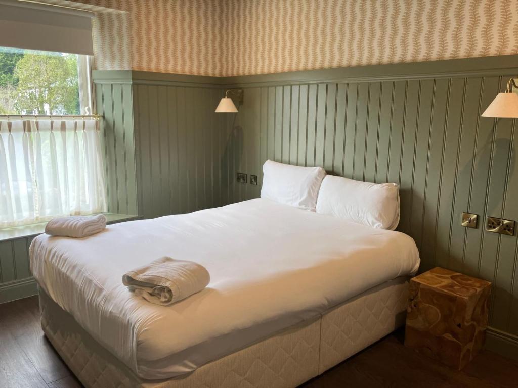 a bedroom with a large bed with white sheets and a window at Horse & Hound in Delgany