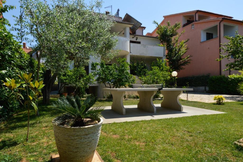 un jardin avec une table et des arbres ainsi qu'un bâtiment dans l'établissement Studio in Pjescana Uvala/Istrien 11166, à Pješčana Uvala