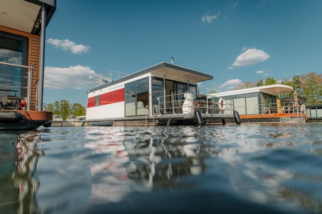 a house on a boat on a body of water at Floatinghouse Red Pearl in Zehdenick