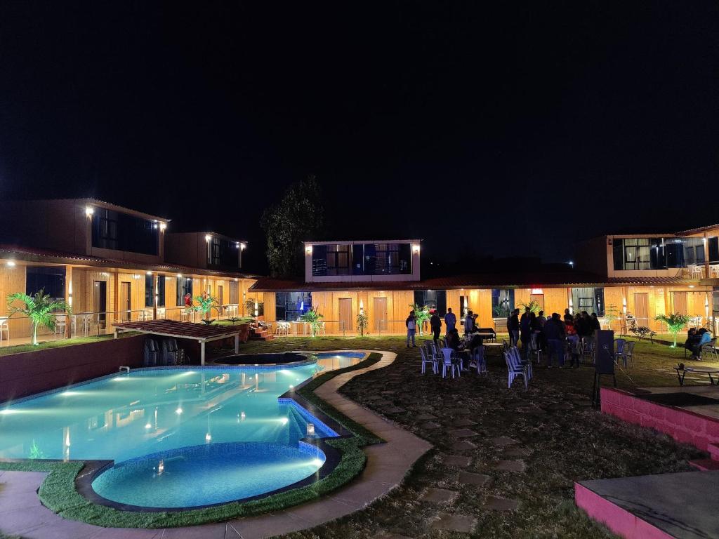 a swimming pool at night with people standing around at Arya Resort And Spaa in Mahabaleshwar