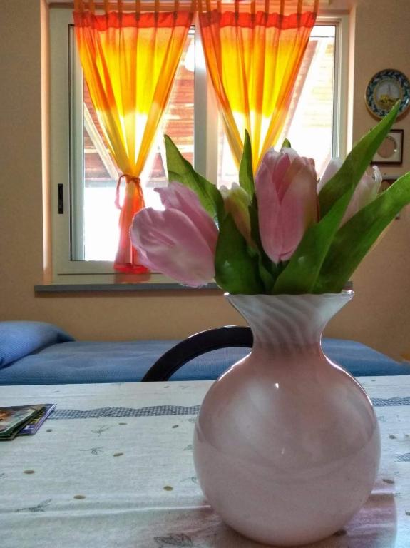 a white vase with pink flowers in it on a table at a casa di Norma in Bronte