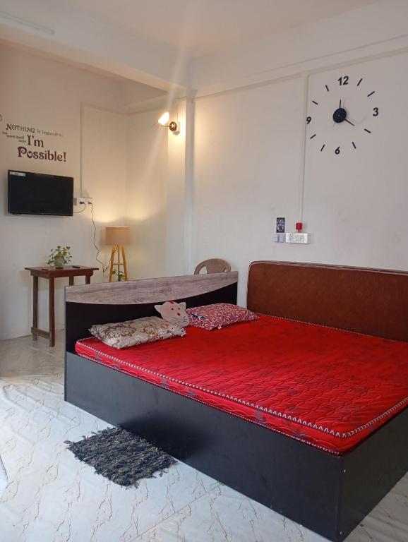 a bedroom with a red bed with a clock on the wall at Green leaf homes in North Lakhimpur