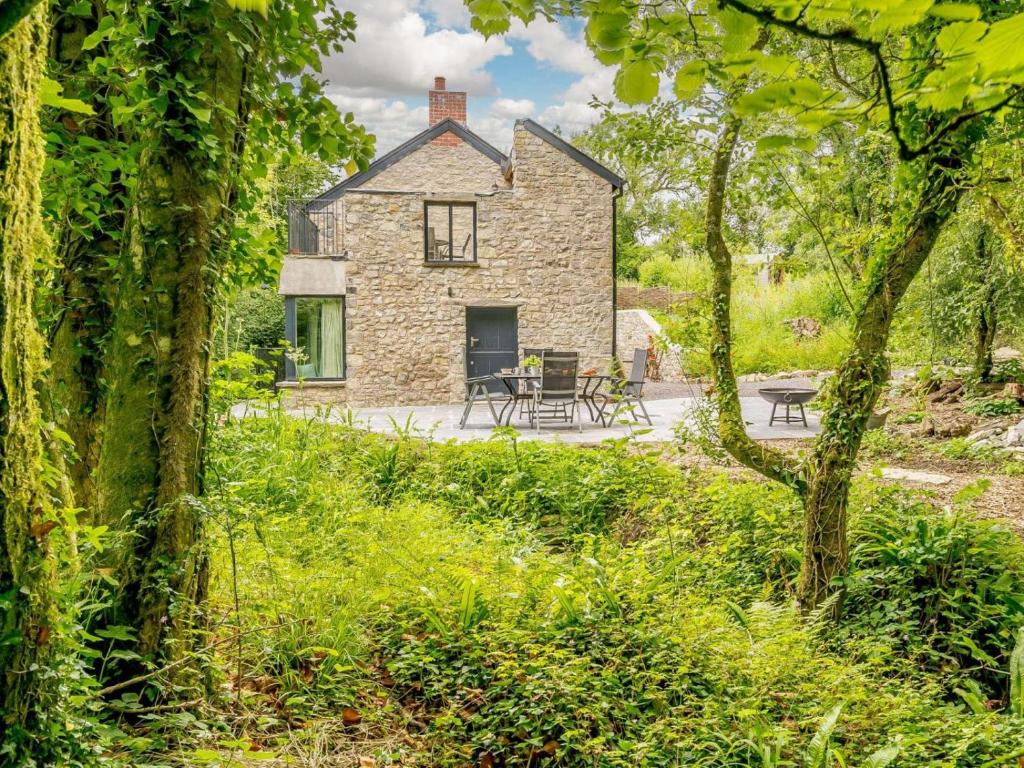an exterior view of a stone house through the trees at 2 Bed in Cowbridge oc-88000 in Llandow