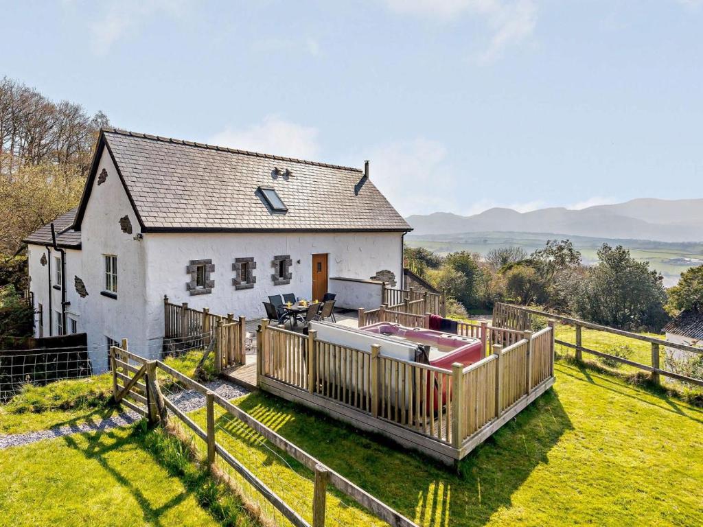 a white house with a wooden fence and a hot tub at 3 Bed in Colwyn Bay oc-74146 in Eglwys-Fâch