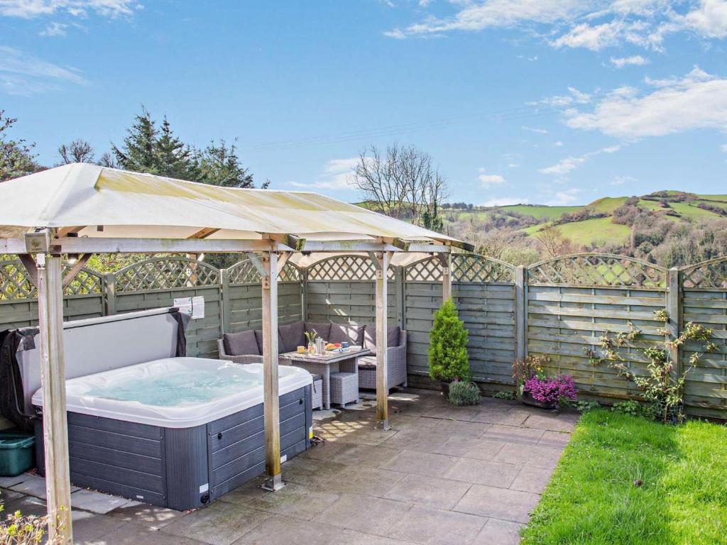 a hot tub under an umbrella in a garden at 4 Bed in Ilfracombe oc-43640 in Berrynarbor