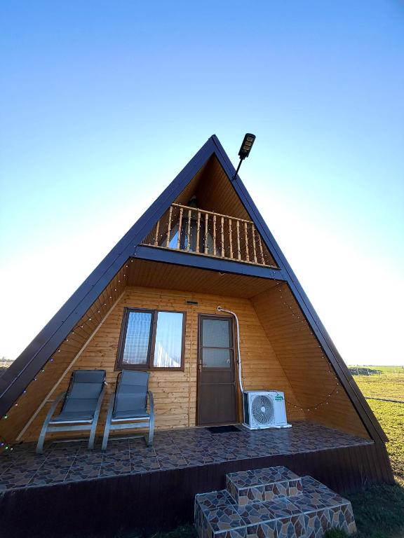 a small house with two chairs and a roof at Șoaptele Naturii A-frame in Buzău