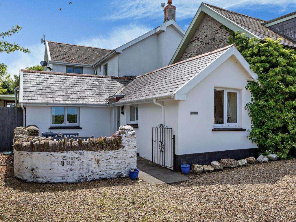a white house with a stone fence in front of it at 1 Bed in Ilfracombe oc-parsc in Berrynarbor