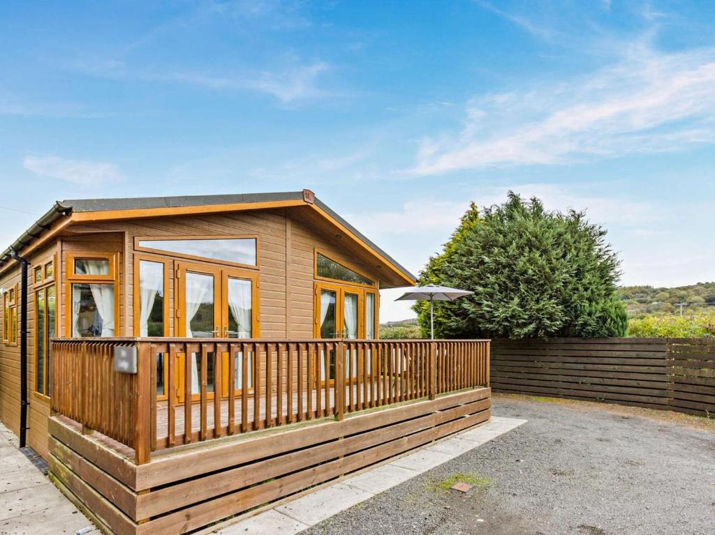 a wooden cabin with a fence in front of it at 2 Bed in Okehampton oc-74242 in Okehampton
