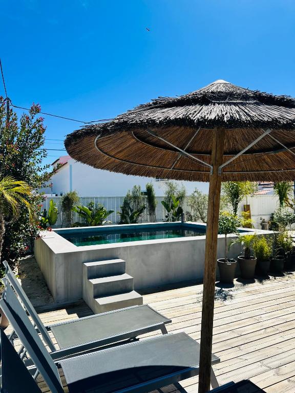 eine Terrasse mit Sonnenschirm und Stühlen sowie ein Pool in der Unterkunft Maison Comporta in Comporta
