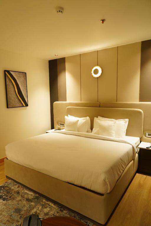 a bedroom with a large bed with white pillows at Hotel Luxe Manor in Mohali