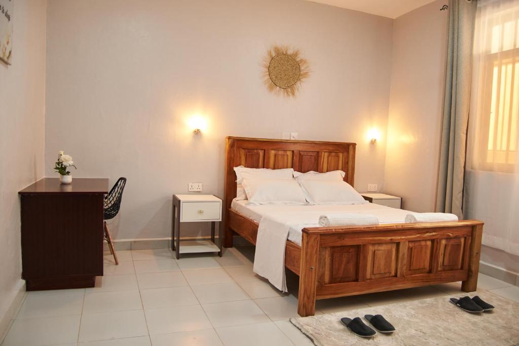 a bedroom with a large wooden bed and a table at Diani Dream stays 2 in Diani Beach