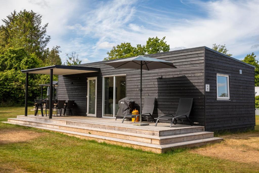 a small black house with an umbrella on a deck at DCU-Camping Hesselhus in Silkeborg