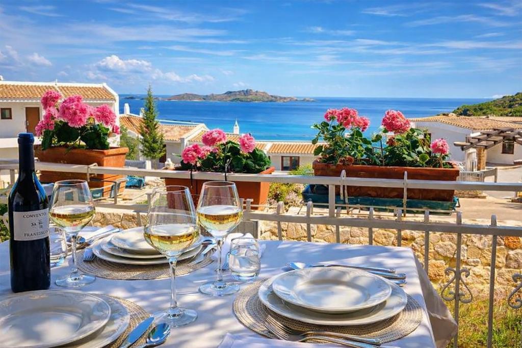 a table with glasses of wine and a view of the ocean at Villa Rena Bianca in Baja Sardinia