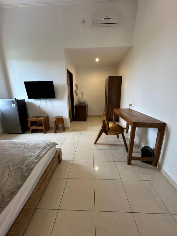 a bedroom with a bed and a table and a desk at Muno House in Seminyak