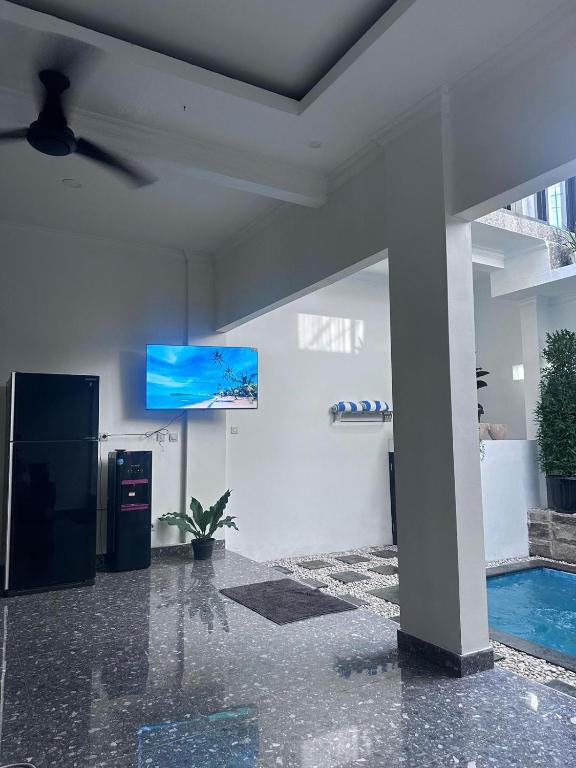 a living room with a tv and a swimming pool at Villa Manis in Denpasar