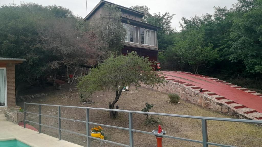 a house with a tree in front of a building at Cuesta Blanca cabañas in Cuesta Blanca