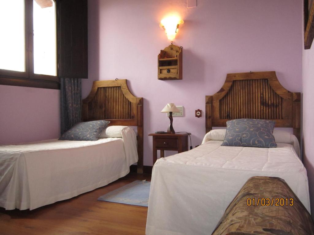 a bedroom with two beds and a lamp on the wall at Hostal Rural Jarpar in Grajera