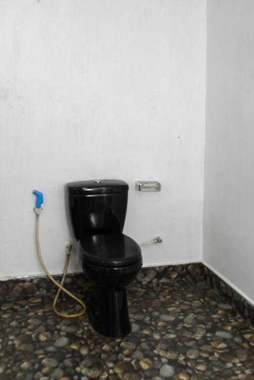 a black toilet in a bathroom with a hose at Shiny cot resort in Nuwara Eliya