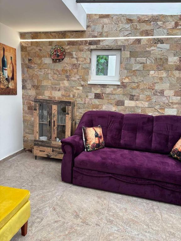 a purple couch in a living room with a stone wall at Tokaj Lamour in Tokaj