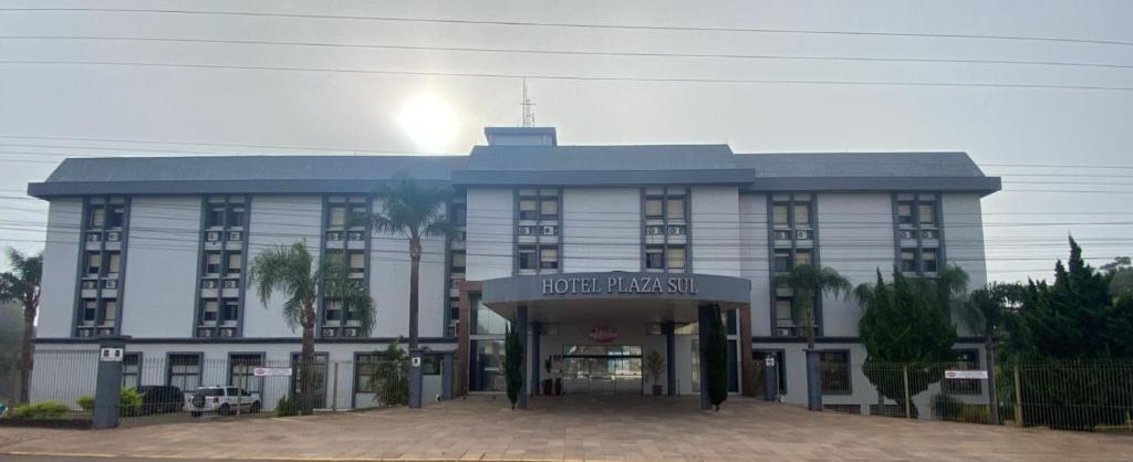 a building with a hotel front with palm trees in front at Hotel Plaza Sul in Caràzinho