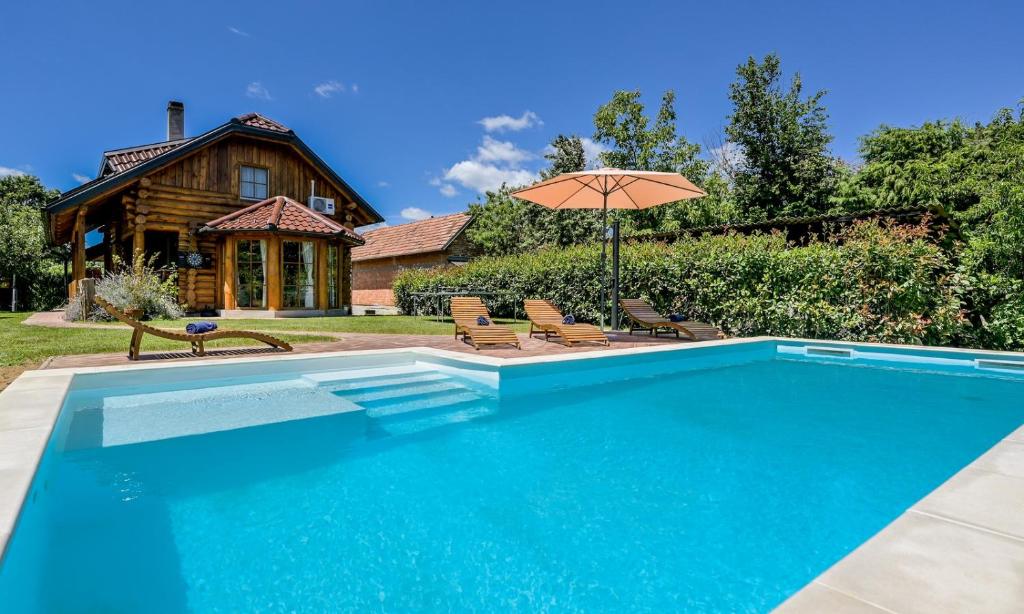 a swimming pool with an umbrella in front of a house at Kuća lješnjaka in Ludbreg