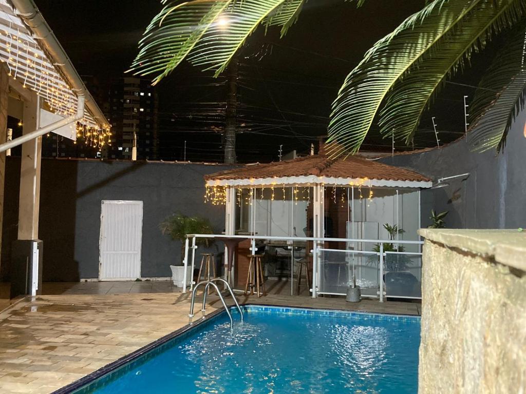 a swimming pool with a table and an umbrella at Casa 100mtrs do mar com piscina aquecida in Solemar