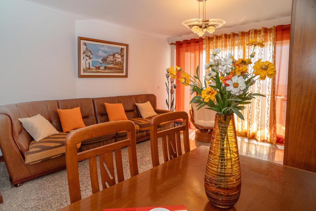 a living room with a couch and a vase of flowers on a table at Brisa de Sesimbra - Spacious Family Apartment, 5min Walk to the Beach with Private Parking in Sesimbra