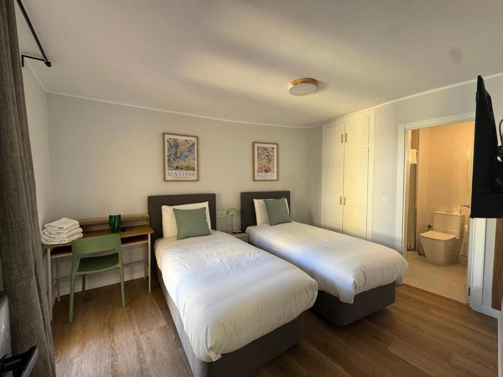 two beds in a room with a desk and a bed at Hostal Guzman El Bueno by gaiarooms in León