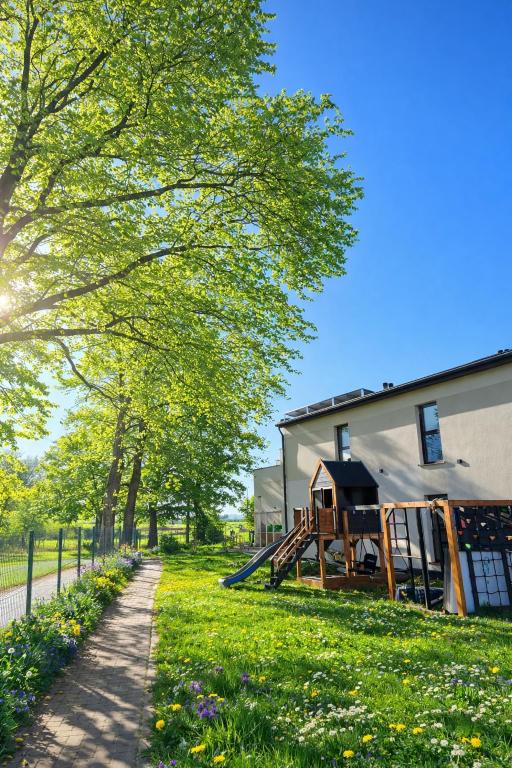 a house with a playground in the grass next to a building at Bursztynowy Horyzont Śliwin obok Rewal , Pobierowo in Śliwin