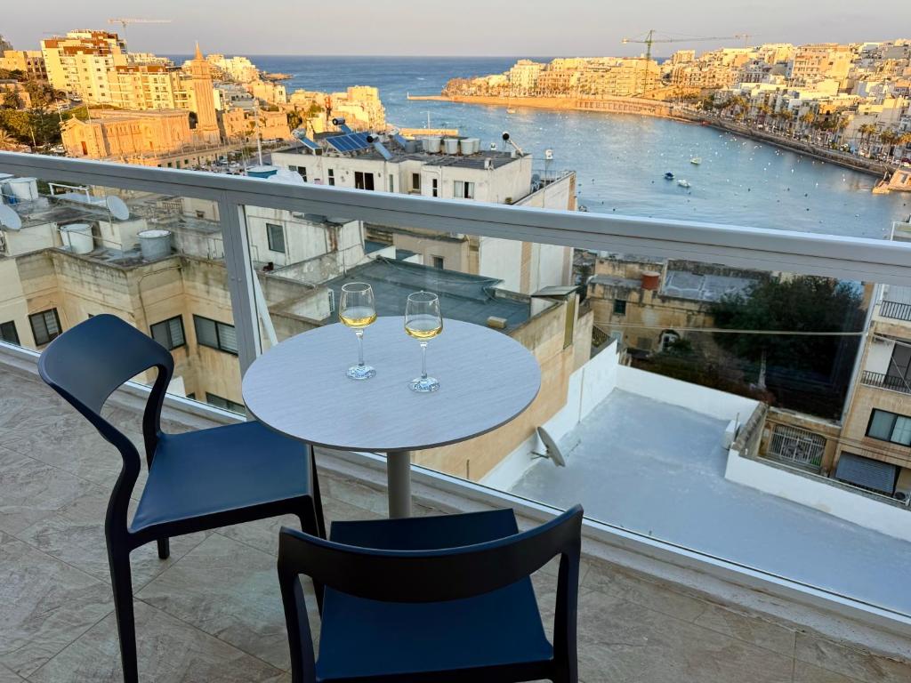 a table with two glasses of wine on a balcony at Serenità - Seaview Penthouse in Marsaskala