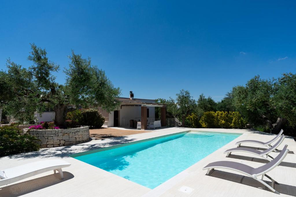 a swimming pool with two chairs and a house at Villa Irma with Private Pool by Wonderful Italy in Noci