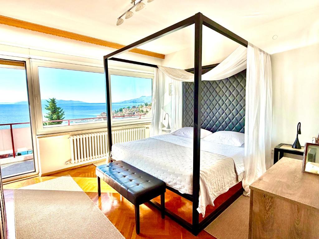 a bedroom with a canopy bed with a view of the ocean at Blue View Apartment in Opatija