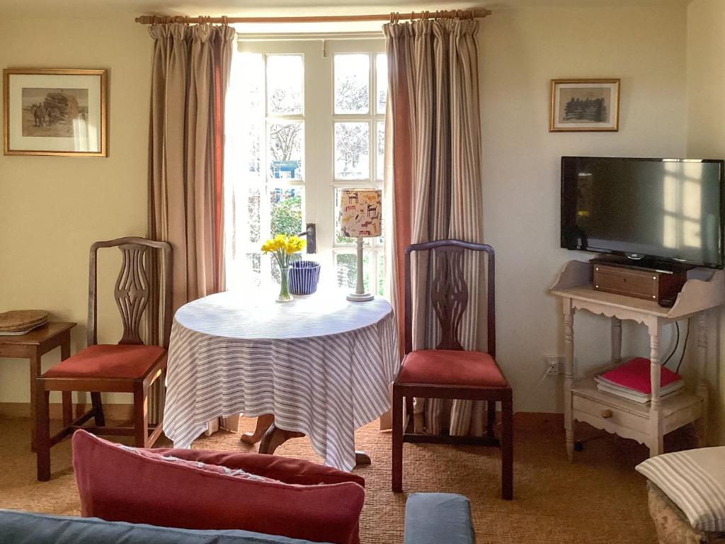 a living room with a table and chairs and a tv at Stepping Gate Cottage in Scalby