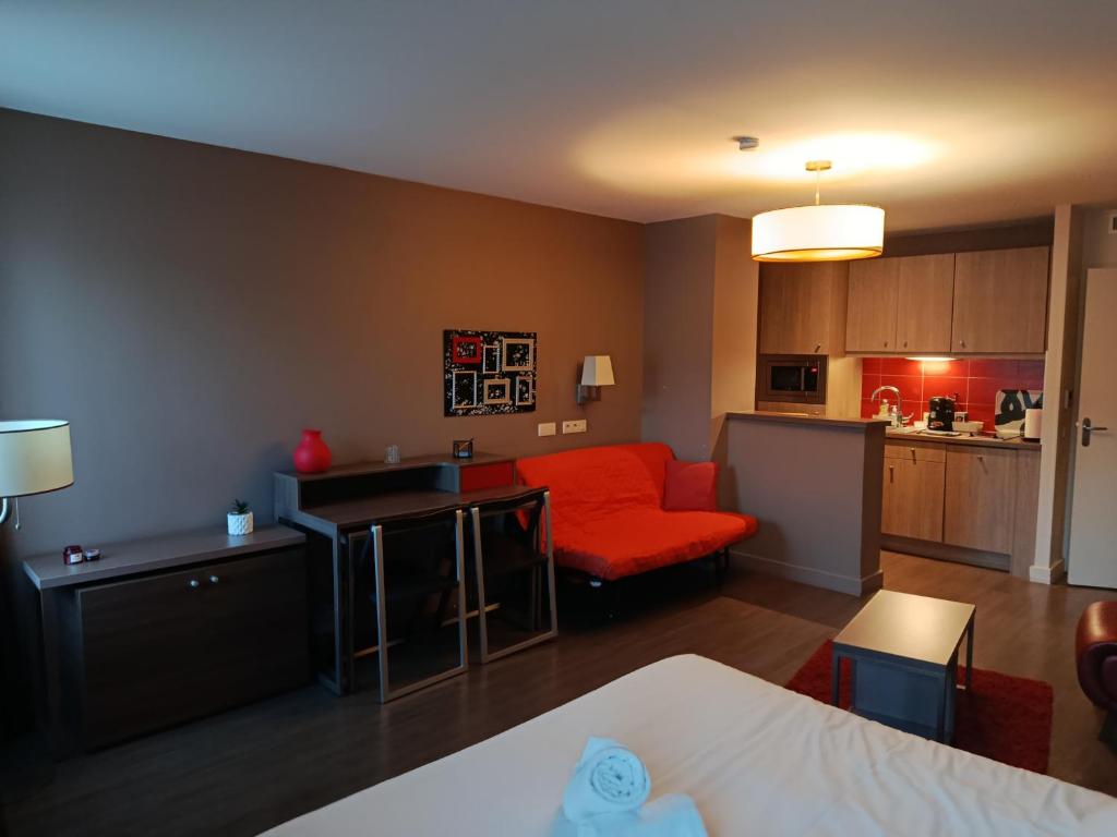a living room with a red couch and a kitchen at Studio au-dessus de l'Orne in Caen